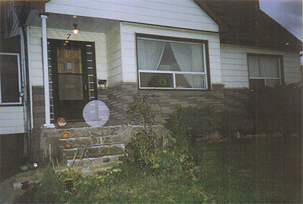 Close view of a house with pumpkins on the cement steps, and a strange orb of light.