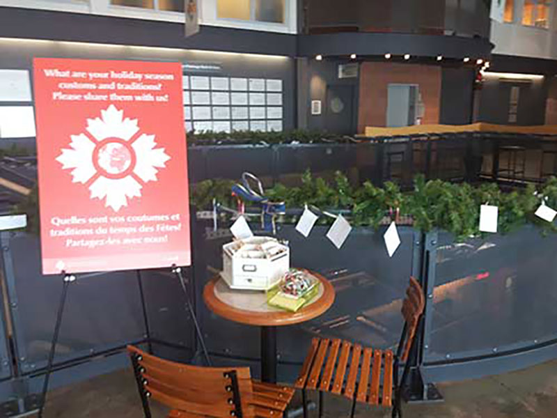 Two chairs and a round table close to the board logo sign of the Canadian Museum of Immigration at Pier 21.