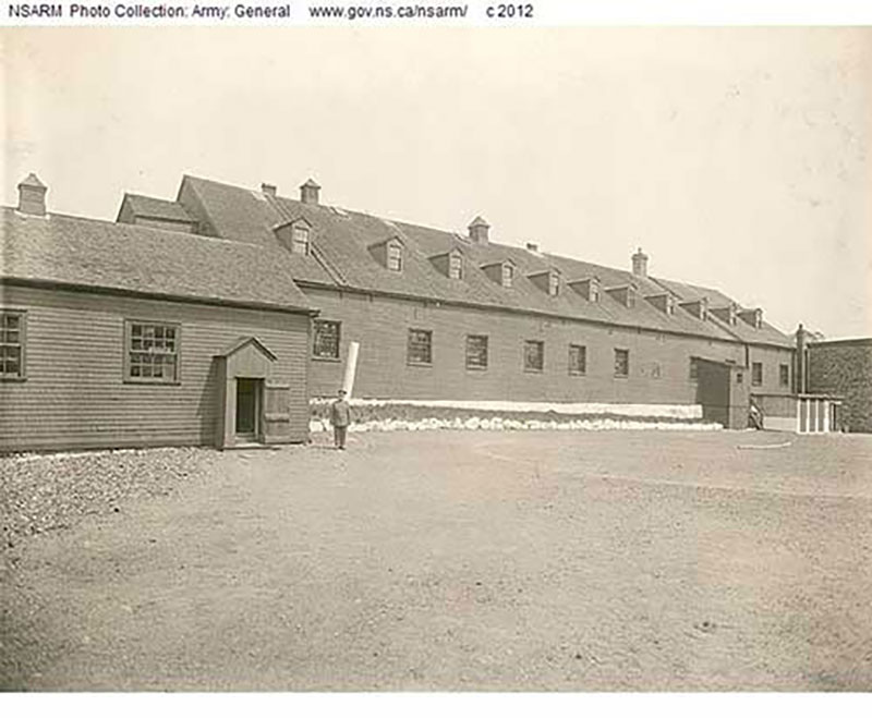 A man is standing in uniform in front of a big building.