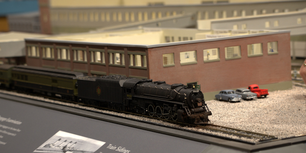 
A miniature model of brick buildings with a model train in front.
	