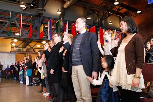 People standing and taking the oath of citizenship at the Pier 21.