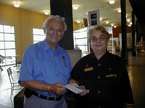 An older smiling couple stand in the Pier 21 Museum.