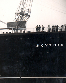 A big ship with the name Scythia pulls into port.