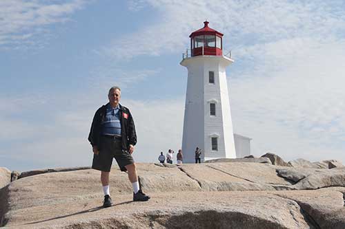 Man standing on rocks close to the Peggy’s Cove lighthouse.