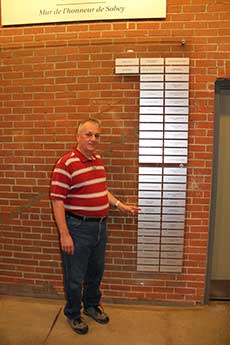 Man standing close to the Sobey’s Wall of Honour and pointing towards it.