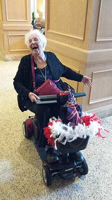 Femme âgée riant alors qu’elle est assise dans un fauteuil roulant avec beaucoup de drapeaux Union Jack attachés.