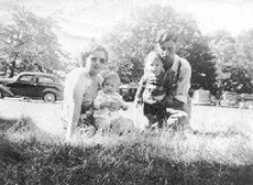 Vieille photo délavée d’un couple et leurs enfants assis sur l’herbe.