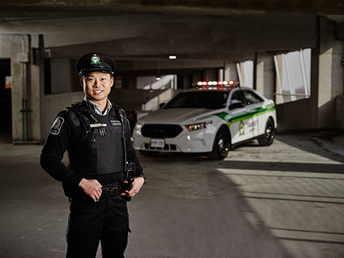 Un policier en uniforme se tient à côté de sa voiture de police et pose pour la caméra.<br />
