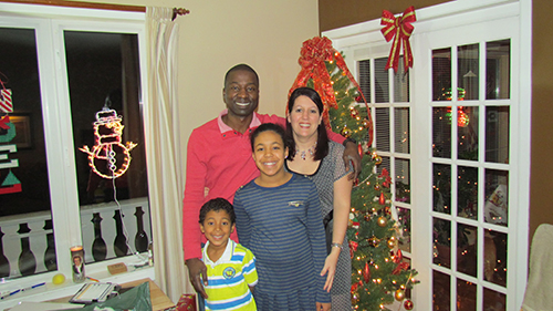 A couple with their children standing beside the Christmas tree.