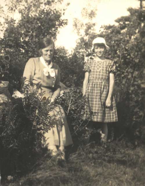 Une jeune femme et une petite fille s’assoient dans un jardin.