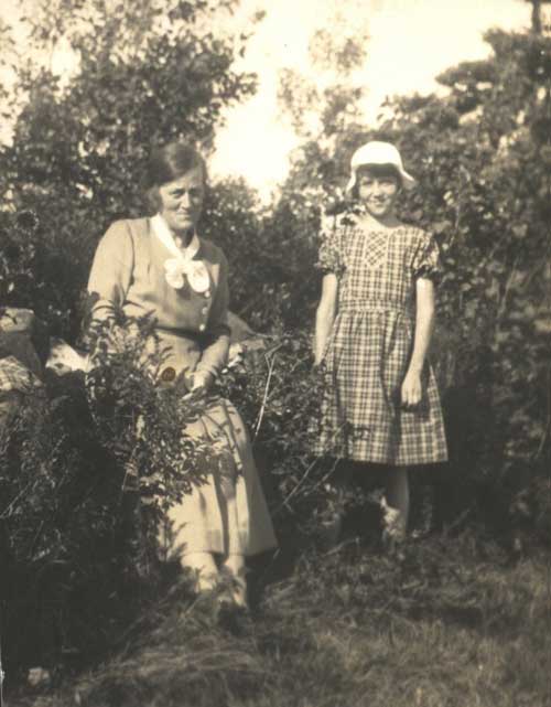 A young woman and little girl sit in a garden.