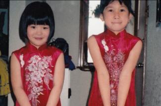 Two little girls dressed in beautiful red silk dresses.
