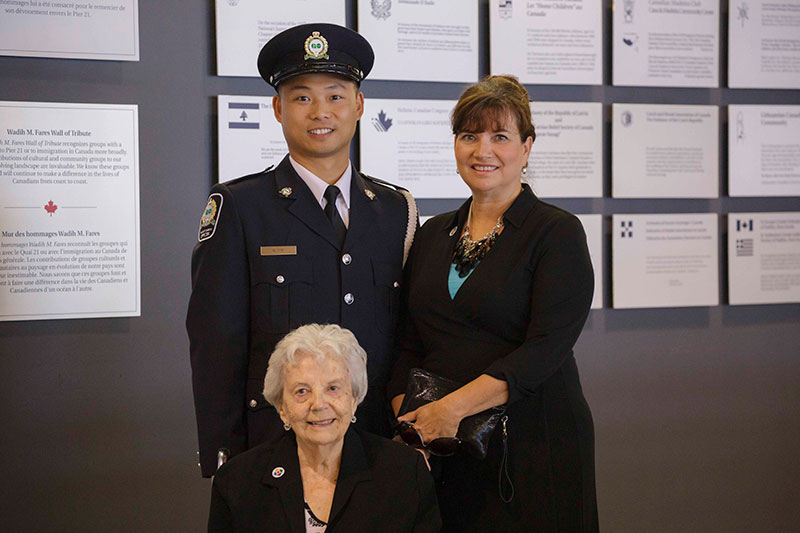 A young man in police uniform stands next to two women.