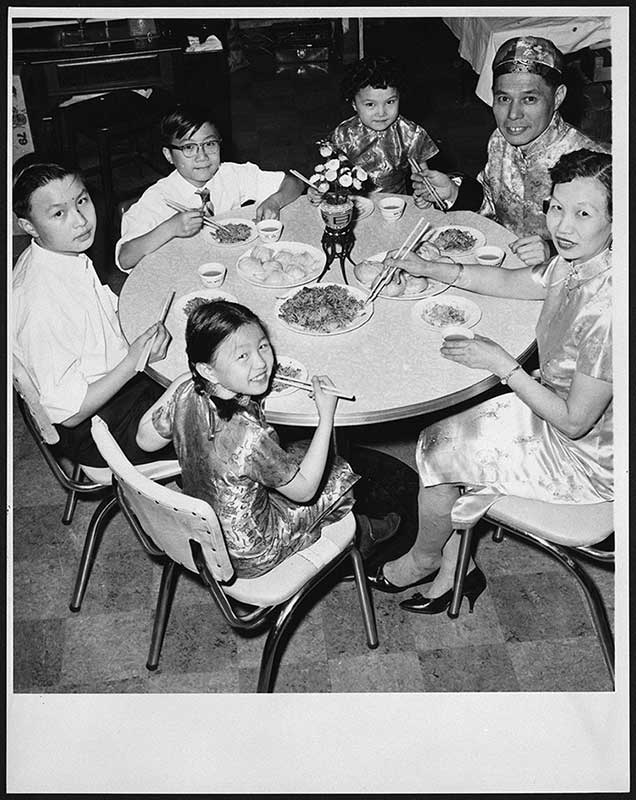 An Asian family is seated for a meal around the dinner table.