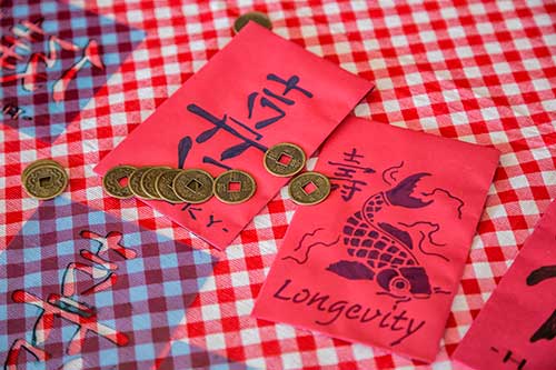 Two decorated red envelopes with coins nearby.