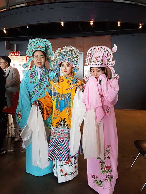 Three young girls dressed in traditional costumes celebrate Lunar New Year.