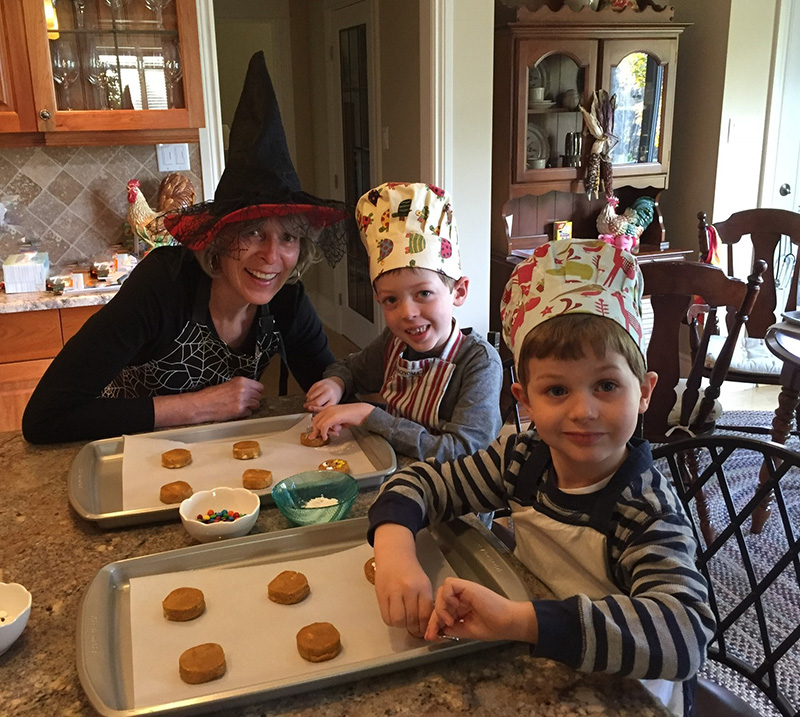 A woman and two young boys make cookies for Halloween.