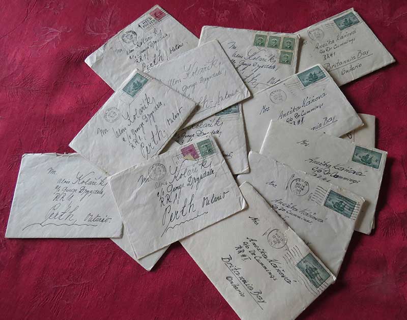 Many letters and envelopes are spread out on a table.